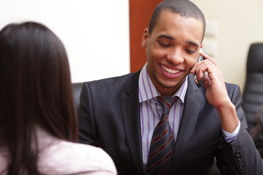Happy african-american businessman on phone in office